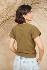 Remera color verde militar de algodón con cuello redondo y mangas cortas. Presenta pequeños apliques dorados en el frente.
