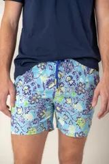 Short de baño celeste con estampado floral en tonos azul, blanco y verde. Tiene cintura elástica con cordón de ajuste azul y detalles amarillos.