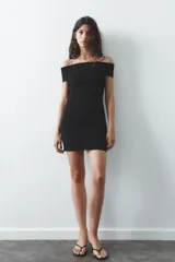 Vestido corto negro de tejido de punto, con escote recto y hombros descubiertos.