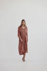 Vestido camisero color marrón con estampado de cadenas blancas, cuello camisero, mangas largas y lazo para ajustar en la cintura.