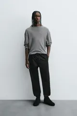 Pantalón jogger negro de corte slim fit, confeccionado en tejido de algodón con cintura elástica ajustable con cordón, bolsillos frontales y traseros de vivo, y bajo con puño elástico.