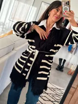 Sacón negro con rayas horizontales blancas, tejido tipo mohair, corte oversize y cinturón ajustable.