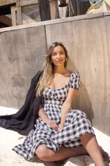 Vestido corto con estampado a cuadros blanco y negro, espalda descubierta con tiras cruzadas y falda acampanada.