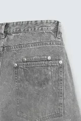 Pantalón de jean gris con efecto lavado, corte amplio tipo balloon fit, tiro medio, cinco bolsillos y cierre frontal con cremallera y botón.