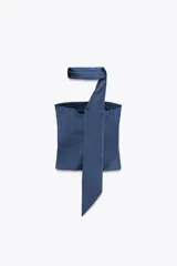 Top azul de satén con escote recto y hombros descubiertos. Tiene detalle de bufanda en el cuello y cierre lateral con cremallera oculta.
