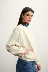 Chaqueta bomber negra con cierre frontal dorado y mangas largas con puños elásticos.