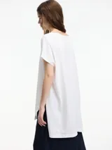 Remera blanca de algodón, corte amplio y largo irregular con tajos laterales.