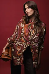Camisa de seda de algodón estampada con arabescos en tonos marrones, verdes, naranjas y dorados. Tiene corte holgado, abertura frontal y lurex dorado.