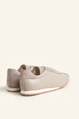 Zapatillas deportivas de cuero color borgoña con detalles en gamuza al tono, cordones finos y suela de goma blanca.