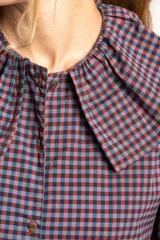 Camisa a cuadros azul y rosa con cuello babero, mangas largas abullonadas y cierre frontal con botones.