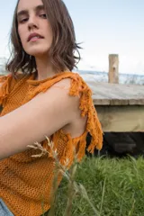 Musculosa color ladrillo de tejido calado con flecos en los hombros y cuello redondo.