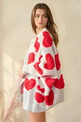 Sweater cardigan oversize color gris con estampado de corazones rojos.