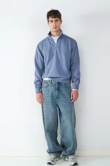 Buzo celeste de corte relajado con media cremallera frontal y cuello subido. Confeccionado en tejido suave con acabado efecto lavado. Puños acanalados y bajo elástico para un mejor ajuste.