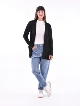 Saco color beige de tejido de punto, con cuello abierto, bolsillos frontales y mangas largas con detalle de botones en los puños.