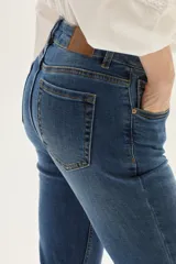 Jean de tiro medio, color azul medio, con silueta ligeramente acampanada desde la rodilla.