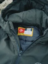 Campera verde oscuro con estampado de dibujos en blanco en el frente. Corte recto, con cierre frontal y bolsillos laterales con cierre.