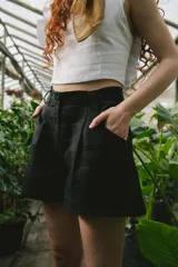 Short negro de tiro alto con pinzas frontales, bolsillos laterales y presillas.