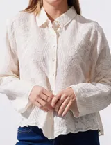 Camisa de manga larga color beige, con bordado tipo broderie, cuello con solapa y abertura central con botones.