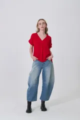 Blusa holgada de poliéster color blanco, con escote en V profundo y pinzas frontales que generan caída. Mangas cortas.