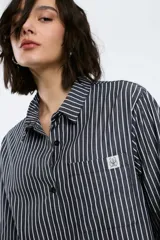 Camisa a rayas verticales rojas y blancas, de corte recto, con cuello clásico, manga larga y bolsillo en el pecho.