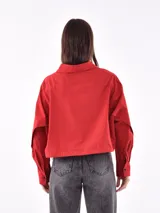 Camisa corta a la cintura, a rayas verticales azules y blancas, con cuello clásico y cierre frontal con botones negros.