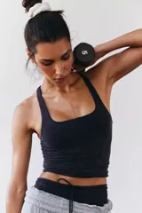 Top deportivo ajustado de tejido de punto liso y elástico, color negro con efecto desgastado. Presenta un escote cuadrado pronunciado y breteles anchos.