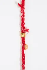 Cadena para lentes de tela estampada con diseño paisley en tonos rojos y blancos, con detalles de cuentas doradas, negras y de madera.