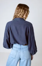 Camisa blanca de lino y lyocell, de corte clásico, con cuello camisero y mangas largas abullonadas con puños abotonados.