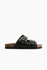 Sandalias negras con dos tiras ajustables con hebillas doradas. Plantilla color café y suela con diseño.
