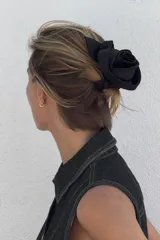 Coletero elástico negro con aplique de flor y hoja en relieve.