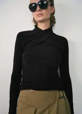 Remera negra de cuello alto cruzado, entallada y de manga larga.