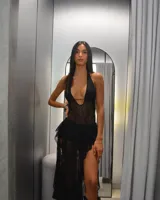 Vestido negro de encaje con escote halter, abertura lateral y falda asimétrica.