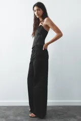 Top bustier negro de satén con escote corazón y hombros descubiertos. Cierre trasero con cremallera metálica.