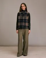 Chaleco sin mangas acolchado con estampado a cuadros en tonos negro, marrón y beige. Presenta detalles western y flecos en la parte superior. Tiene bolsillos de parche frontales y cierre con botones.