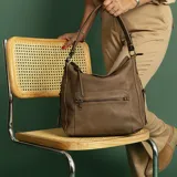 Cartera negra de cuero sintético con apertura superior y cierre con solapa. Tiene un bolsillo frontal con broche magnético y cierre, dos bolsillos internos y un bolsillo divisor en el forro. Incluye bolsillos laterales con cierre y correa larga regulable.