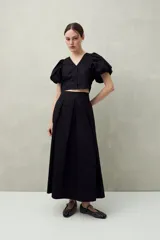 Falda midi negra de corte evasé con pliegues.