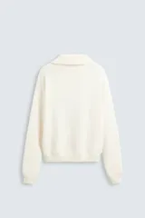 Sweater color crema de punto con cuello polo y escote en V.