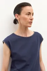 Remera de manga corta color azul marino con cuello redondo y bordado de pespunte en contraste color beige alrededor del cuello y los bordes de las mangas.