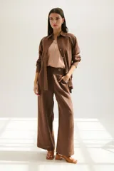 Pantalón de lino azul de corte palazzo con botón decorativo en la cintura.