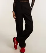Pantalón de vestir blanco, de corte recto, con bolsillos laterales y traseros. Se ajusta a la cintura con cierre tradicional.