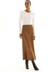 Pollera midi color marrón con leve brillo y caída suave. Modelo de tiro alto con elástico oculto en la cintura y leve vuelo en el bajo.
