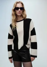 Sweater de punto con diseño a rayas verticales en blanco y negro, de corte recto y cuello redondo.