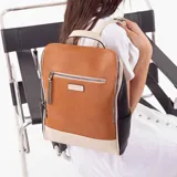 Mochila combinada en tres tonos: marrón, beige y negro. Tiene un bolsillo frontal con cierre, asa de mano y correas regulables.