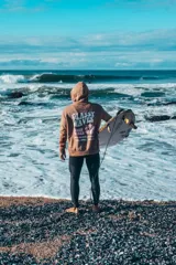 Buzo hoodie marrón con capucha y cordones ajustables. Estampado en la espalda con la frase "Glassy Waves", "Good Vibes", una flor y las fechas "1971, 1982, 1993".