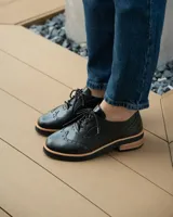 Zapato acordonado color bronce de cuero vacuno con perforaciones decorativas, taco de madera con folia en cuero de 4cm y entre suela de goma de 1,5cm. Horma de punta redonda y cómoda.