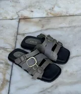 Sandalias bajas de cuero color gris con tres tiras horizontales con hebillas metálicas y plantilla anatómica.