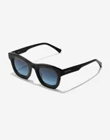 Lentes de sol Hawkers modelo Grid Black, unisex, con montura cuadrada de color negro y lentes degradadas de azul a transparente.