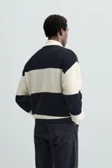 Sweater tipo polo de punto con rayas horizontales anchas en color negro y crudo, con cuello clásico y cierre de dos botones.