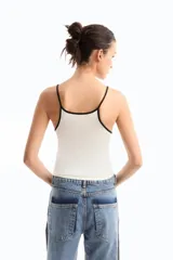 Musculosa negra de jersey de algodón con modal peruano, de calce fitted, escote en "U" y largo a la cadera. Presenta detalle de breteles y escote a contratono en blanco. Cuenta con bordado marcario a contratono en frente como distintivo.