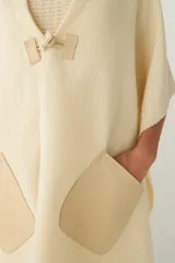 Chal de lana fina sin teñir, con calce en hombros, abrochadura con alamar de fieltro, bolsillos de cuero y terminación con flecos. Diseño exclusivo de Don Baez, hecho en Uruguay.